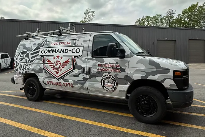 Commercial van wrapped in business graphics and camo style design.