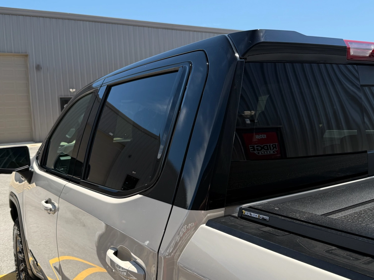 Gloss black tuxedo wrap close up photo of back corner on Sierra truck.